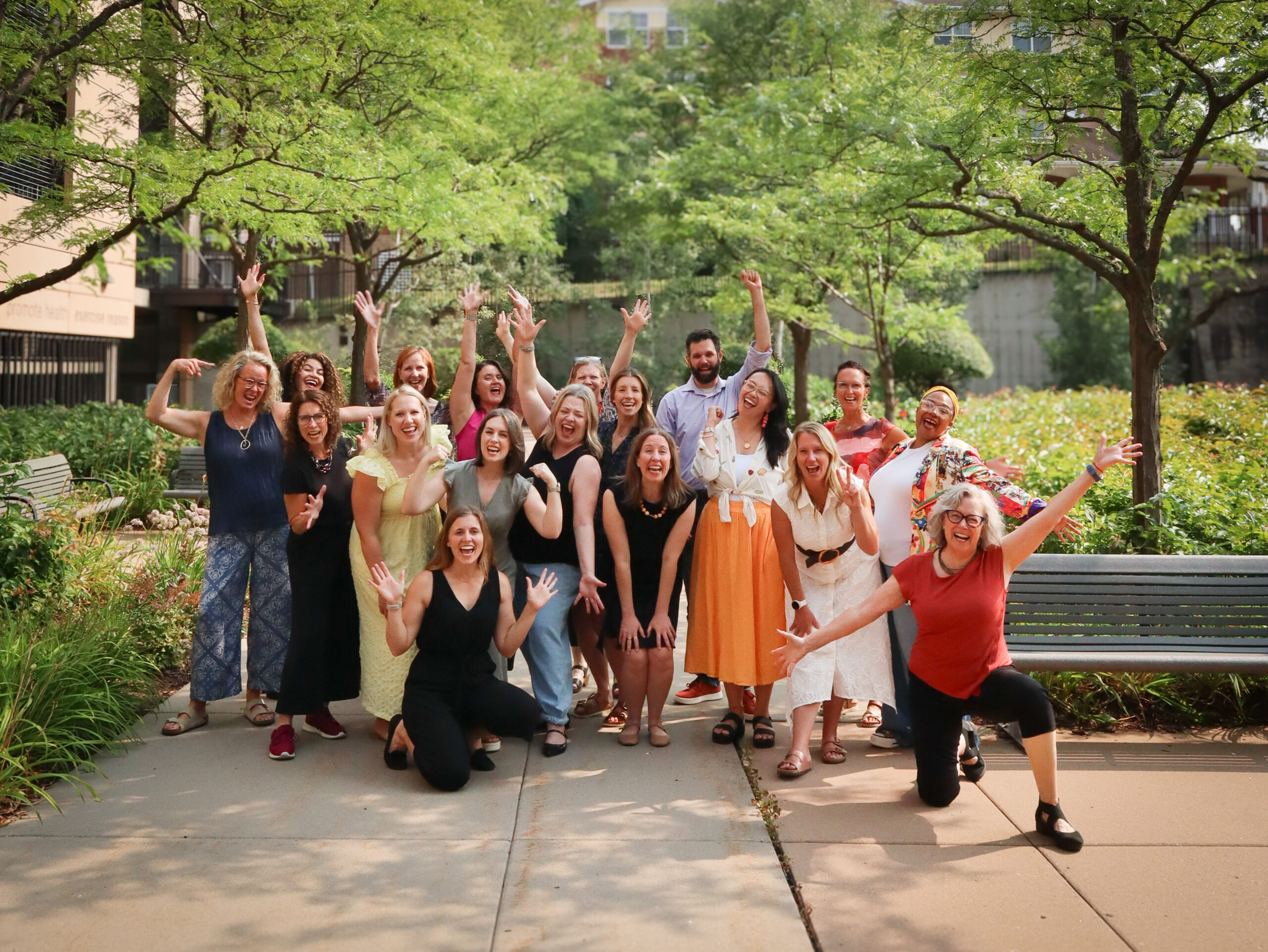 ECO Cohort 10 Graduation Group of CCO community members smiling and celebrating together outdoors in a tree-lined courtyard.